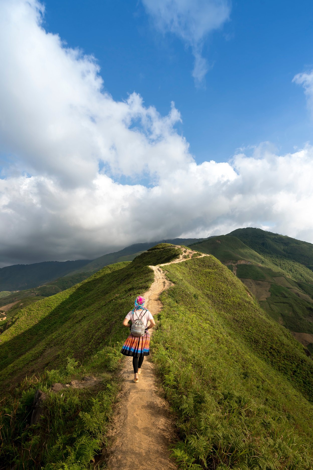 Woman in colorful clothes walking alone on a mountain top on a journey for self knowledge 