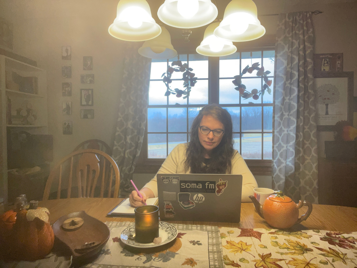 Picture of Coach Tina from Move with Courage Coaching working with a client on a laptop, pumpkin shaped teapot and notebook on the desk.