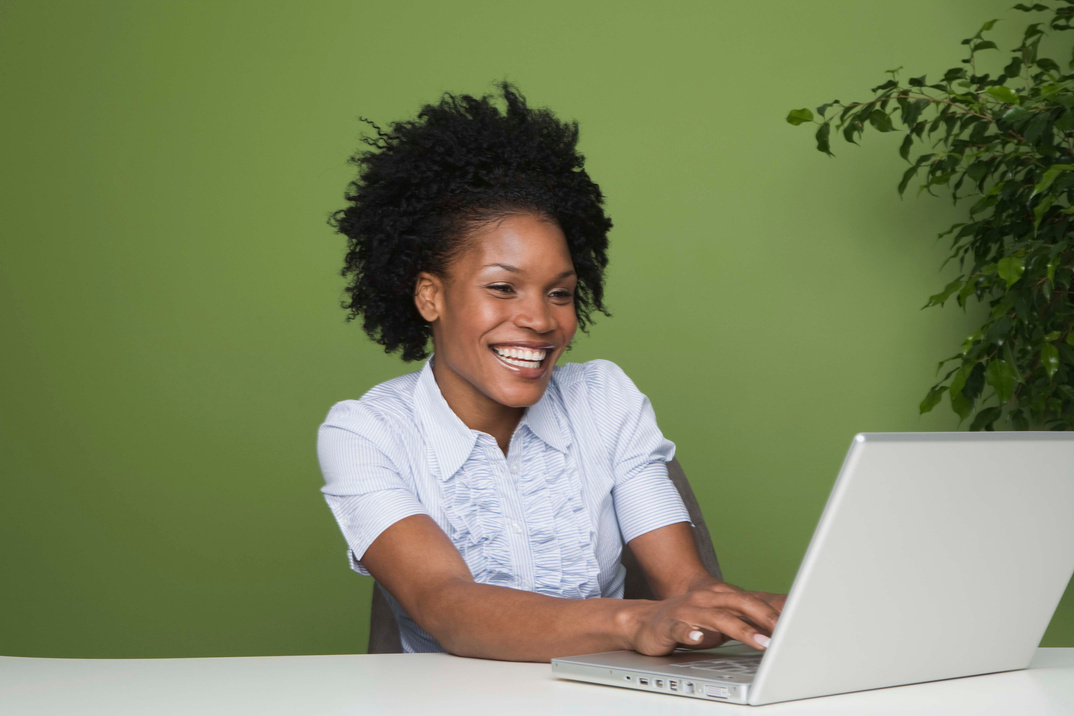 Want to Build Self Confidence? Why it's time to write a new resume. Woman happily updating her resume on a laptop.
