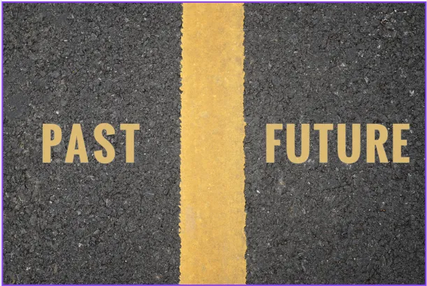 the words past and future are painted on the side of a road, suggesting you are standing in between the past and the future